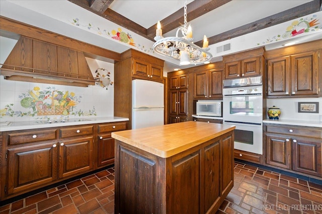 kitchen featuring visible vents, decorative backsplash, stone finish floor, a chandelier, and white appliances