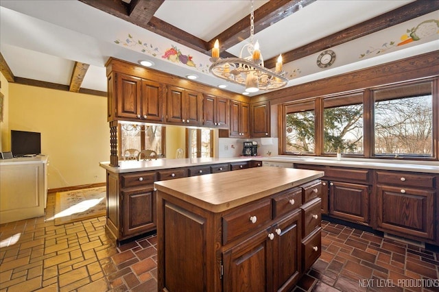 kitchen with a peninsula, butcher block countertops, a kitchen island, baseboards, and beamed ceiling