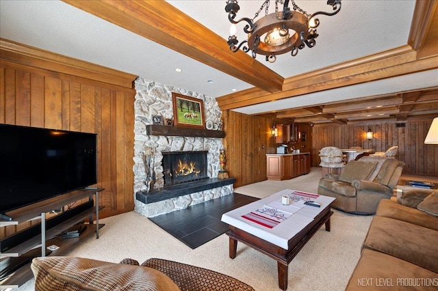 carpeted living room with wood walls, a fireplace, a chandelier, and beam ceiling