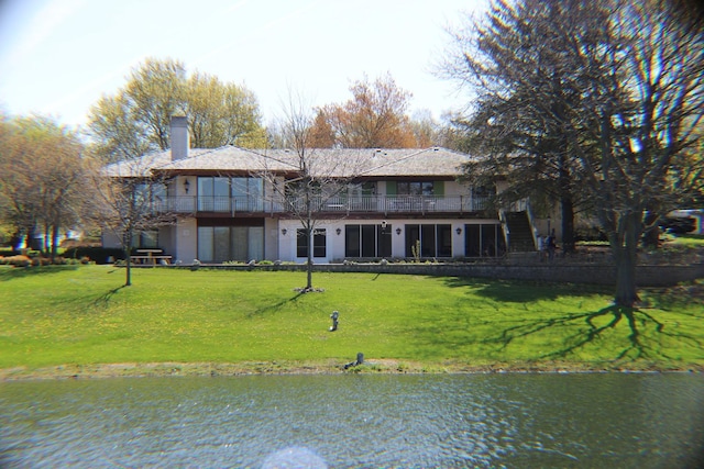 rear view of property with stairway, a yard, a chimney, and a balcony