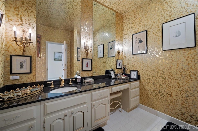 bathroom with a chandelier, vanity, baseboards, tile patterned floors, and wallpapered walls