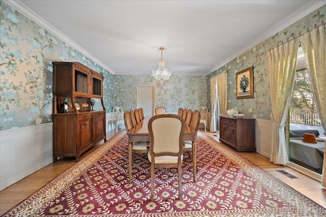 dining area featuring wallpapered walls, a chandelier, and wainscoting