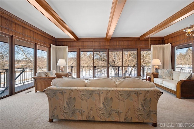 carpeted living area with beamed ceiling, wood walls, and visible vents