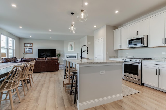 kitchen featuring white cabinetry, an island with sink, appliances with stainless steel finishes, and pendant lighting