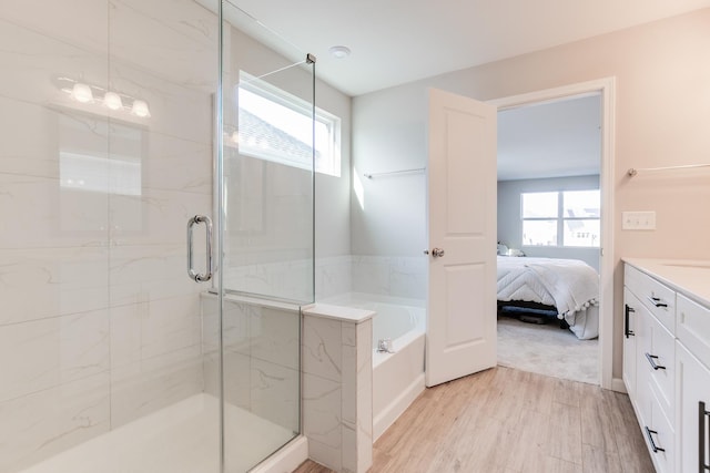 bathroom featuring plenty of natural light, separate shower and tub, wood-type flooring, and vanity