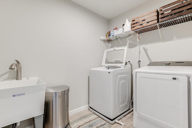 washroom with independent washer and dryer, sink, and light wood-type flooring