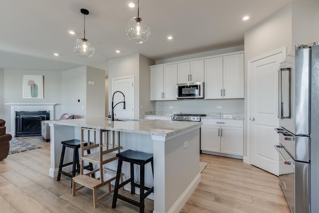 kitchen featuring white cabinetry, sink, hanging light fixtures, a kitchen island with sink, and stainless steel appliances