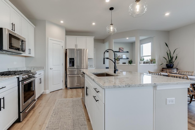 kitchen featuring white cabinetry, appliances with stainless steel finishes, a kitchen island with sink, and sink