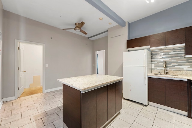 kitchen featuring sink, ceiling fan, backsplash, a kitchen island, and white fridge