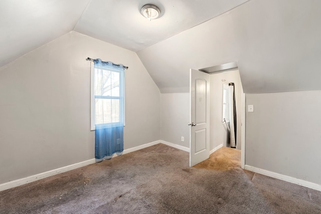 additional living space featuring vaulted ceiling and light colored carpet