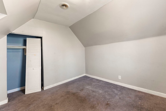 bonus room with dark colored carpet and vaulted ceiling