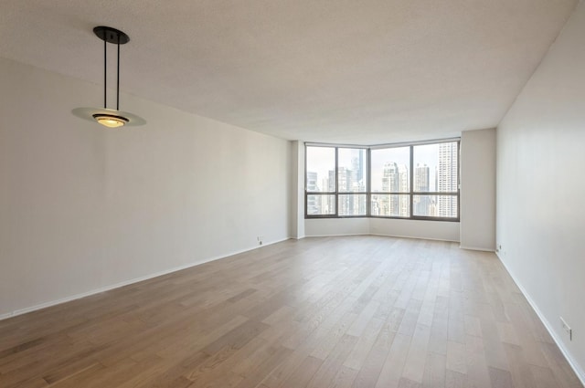 empty room with a view of city, baseboards, and wood finished floors