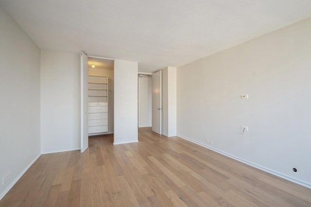 unfurnished bedroom with baseboards, a textured ceiling, and light wood finished floors