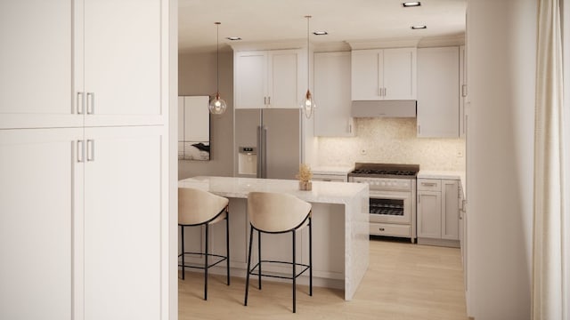 kitchen featuring pendant lighting, high quality appliances, a kitchen breakfast bar, light stone counters, and light hardwood / wood-style floors