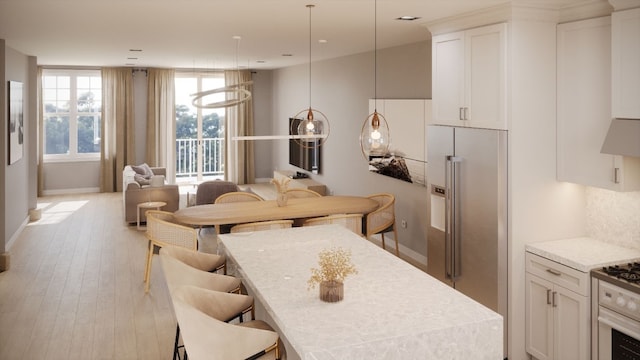 kitchen with pendant lighting, high quality fridge, a kitchen breakfast bar, and white cabinets