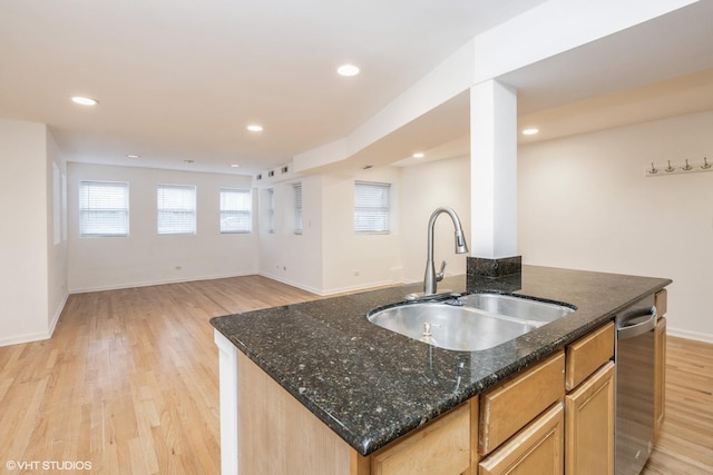 kitchen with sink, dark stone counters, a kitchen island with sink, stainless steel dishwasher, and light hardwood / wood-style floors