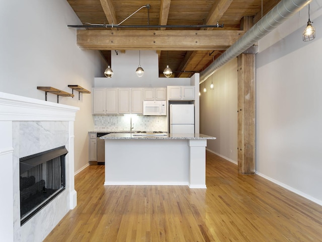 kitchen featuring pendant lighting, beamed ceiling, white cabinets, light stone counters, and white appliances