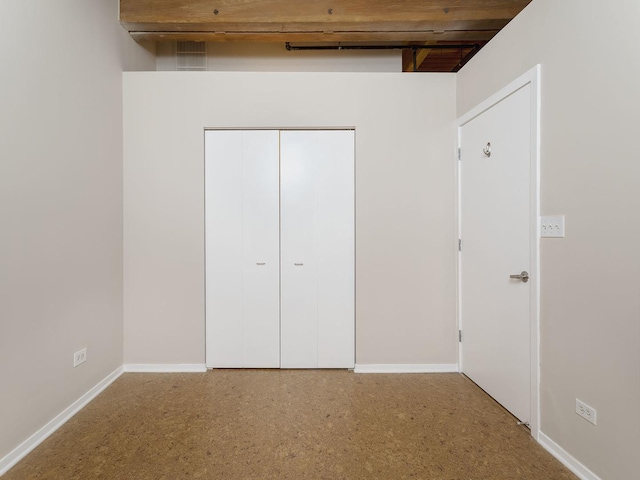 unfurnished bedroom with beamed ceiling and a closet