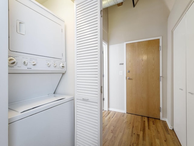 laundry area featuring stacked washer / drying machine and light hardwood / wood-style floors