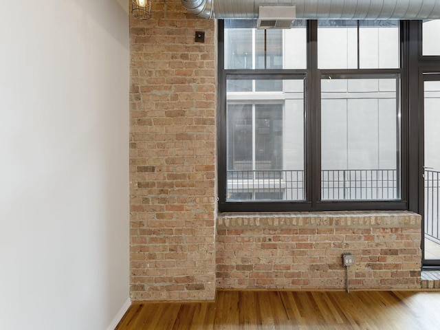 interior space with hardwood / wood-style floors and brick wall