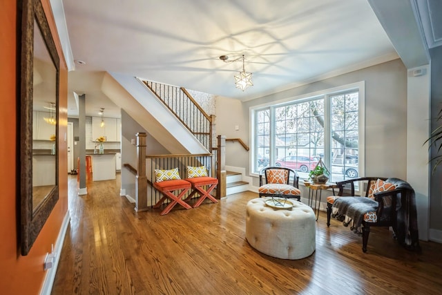 sitting room featuring hardwood / wood-style flooring, crown molding, and a chandelier