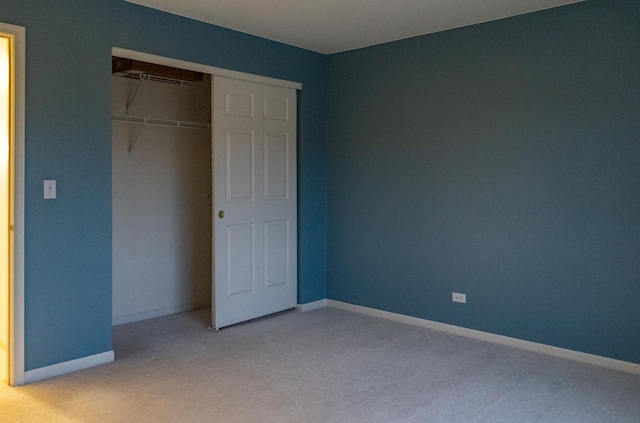 unfurnished bedroom featuring light colored carpet and a closet