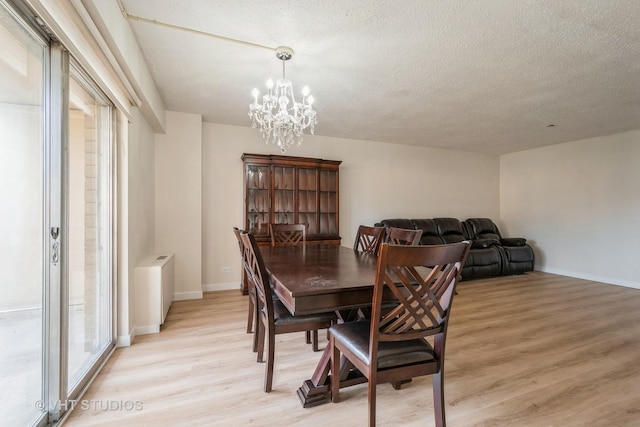 dining space with an inviting chandelier, a healthy amount of sunlight, light hardwood / wood-style flooring, and a textured ceiling