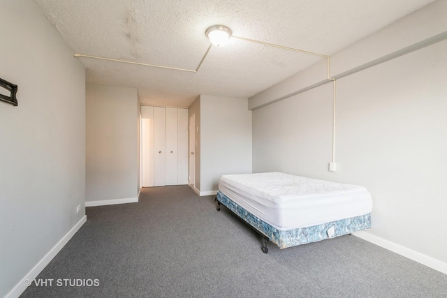 bedroom with a textured ceiling and dark carpet