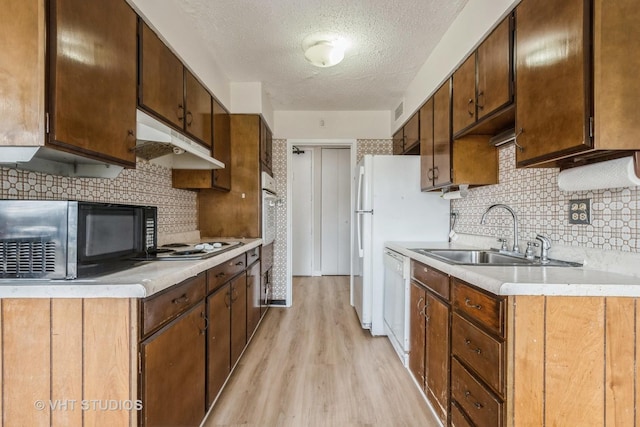 kitchen with sink, light hardwood / wood-style flooring, a textured ceiling, white appliances, and backsplash