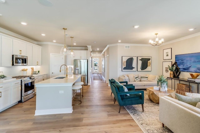 kitchen with white cabinetry, appliances with stainless steel finishes, sink, and a center island with sink