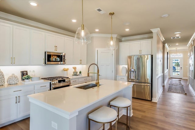 kitchen featuring sink, pendant lighting, stainless steel appliances, a kitchen island with sink, and white cabinets