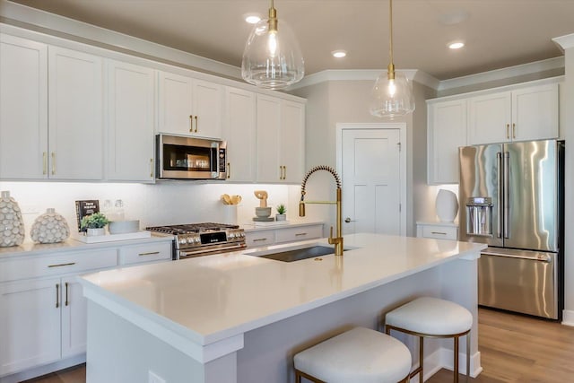 kitchen featuring pendant lighting, stainless steel appliances, white cabinets, and a center island with sink