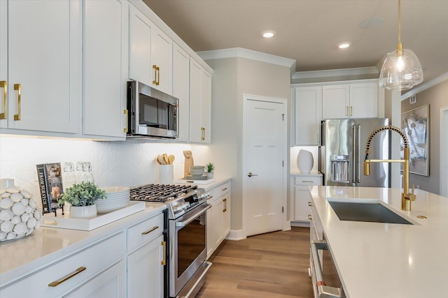 kitchen featuring stainless steel appliances, sink, hanging light fixtures, and white cabinets