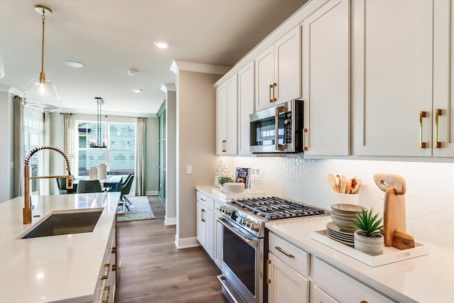 kitchen with pendant lighting, sink, stainless steel appliances, tasteful backsplash, and white cabinets