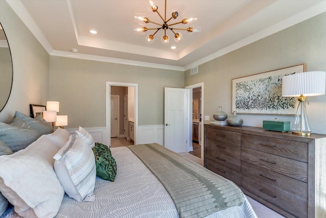 bedroom with crown molding, ensuite bathroom, a tray ceiling, and a notable chandelier