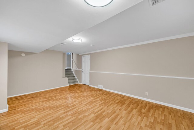 basement featuring crown molding and light hardwood / wood-style flooring