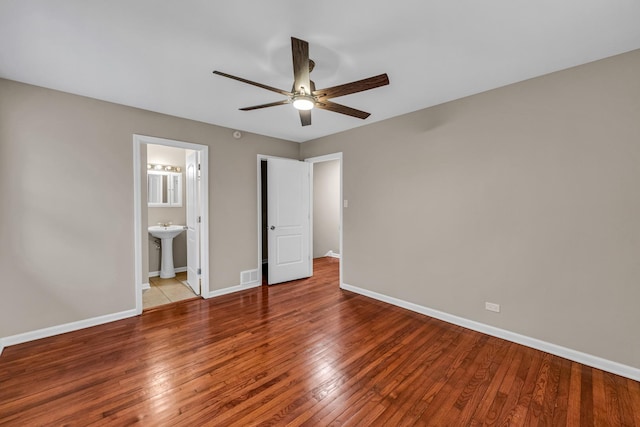 unfurnished bedroom with wood-type flooring, sink, connected bathroom, and ceiling fan