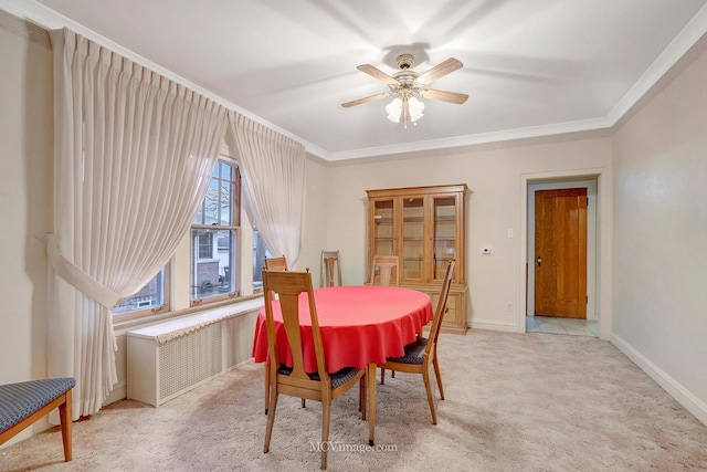 carpeted dining room featuring ornamental molding and ceiling fan