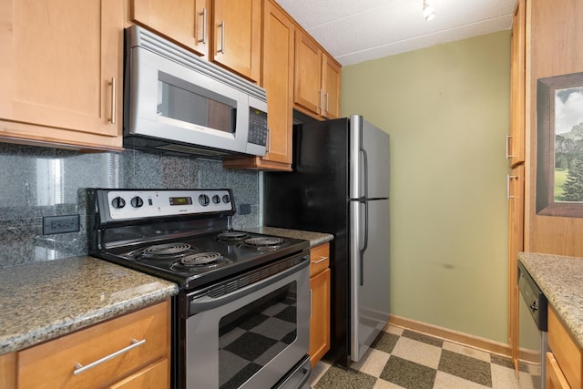 kitchen featuring light stone counters, stainless steel appliances, and backsplash