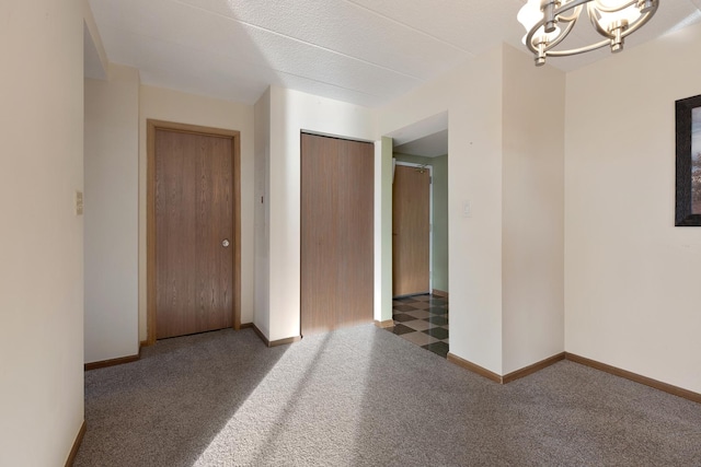 carpeted spare room with a chandelier