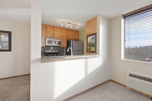 kitchen featuring sink, light carpet, kitchen peninsula, stainless steel appliances, and decorative backsplash