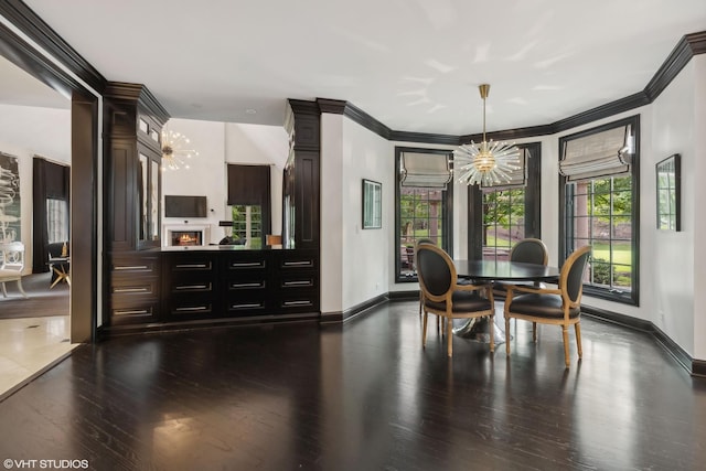 dining space with dark hardwood / wood-style flooring, crown molding, a chandelier, and ornate columns