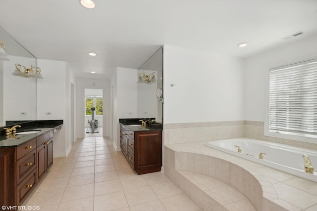 bathroom with tiled tub, vanity, and tile patterned floors