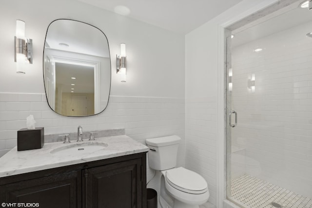 bathroom featuring vanity, toilet, tile walls, and walk in shower