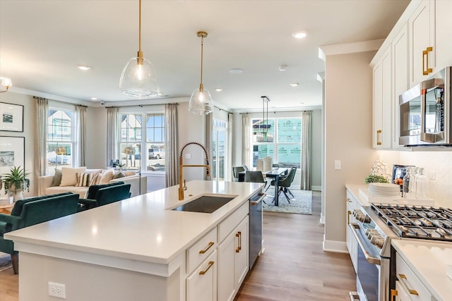 kitchen with stainless steel appliances, an island with sink, sink, and white cabinets