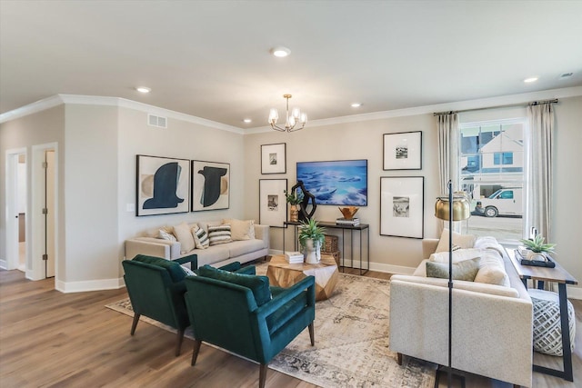 living room with hardwood / wood-style flooring, ornamental molding, and a notable chandelier