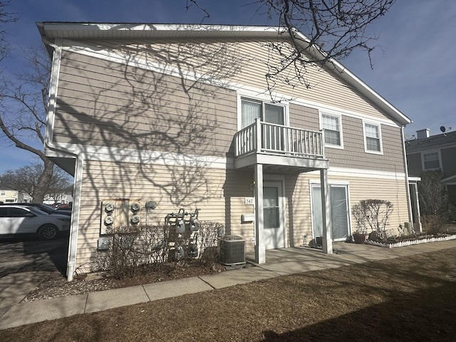 back of house featuring cooling unit and a balcony