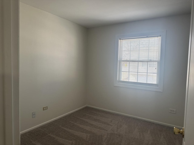 spare room with dark carpet and baseboards