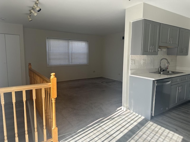 kitchen with dishwasher, backsplash, light countertops, gray cabinetry, and a sink