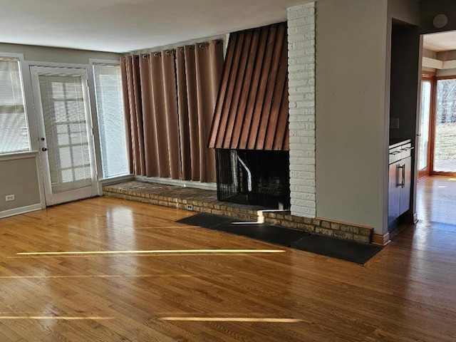 unfurnished living room featuring hardwood / wood-style floors and a brick fireplace